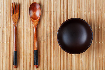 竹盘子摄影照片_天然木盘、勺子和叉子在竹背衬上。