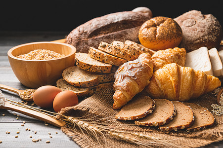 不同种类的面包与木制背景下的营养全谷物。
