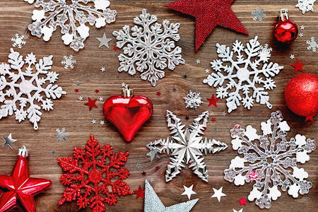圣诞节和新年背景与圣诞装饰-球、星星、银色闪闪发光的雪花、心和木桌上的五彩纸屑。