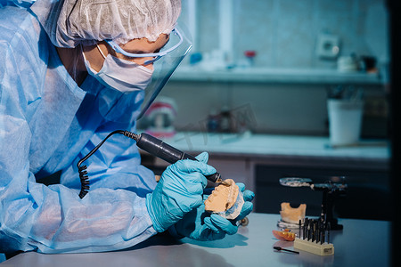 一名身穿防护服的牙科技师正在他的实验室研究假牙