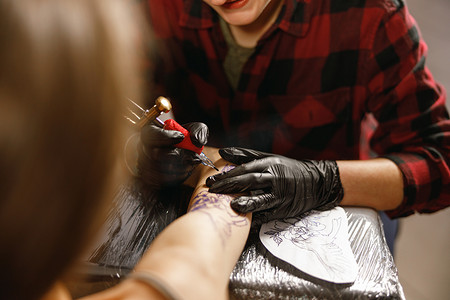 纹身师手用纹身机仔细绘制的特写