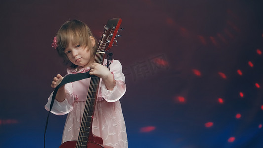 穿着粉色复古连衣裙的小女孩像低音提琴一样弹着原声吉他