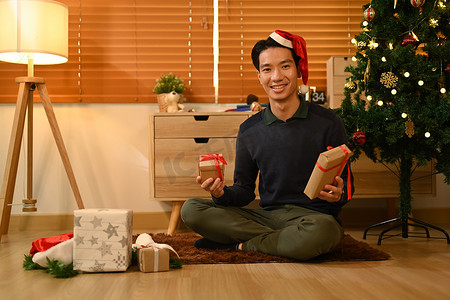 性格开朗的男人坐在客厅的地板上准备圣诞礼物。
