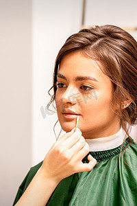 化妆师用棉签将口红固定在女性嘴唇上。