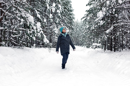 一个女人走在冬天白雪皑皑的森林里。