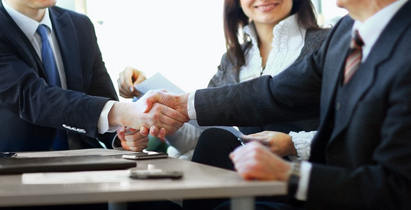 成熟的商人在现代办公室握手与合作伙伴和同事达成协议