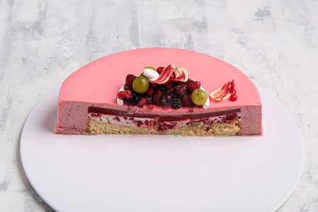 霜果实摄影照片_托盘上用浆果装饰的半个浆果老鼠粉色蛋糕的角度拍摄。