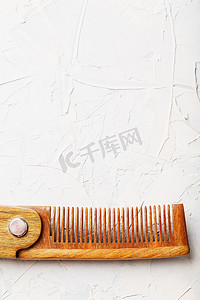 木制檀香木梳子折叠在白色带纹理的背景上。