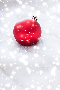 蓬松毛皮上的红色圣诞小玩意，雪花闪闪发光，奢华的冬季假期设计背景