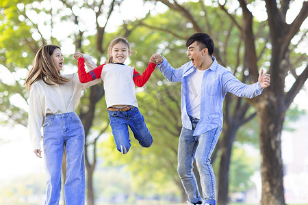 幸福的家庭在公园里一起跳跃和玩耍