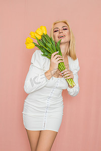 身穿春白裙的金发女人手里拿着花束