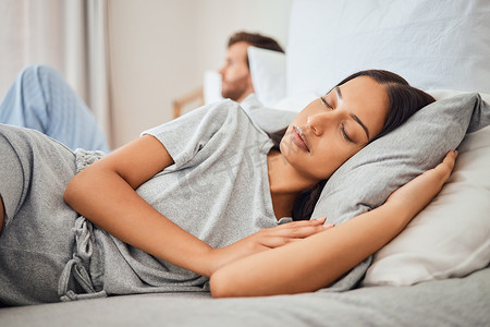 古人枕头摄影照片_睡觉，平静，女人睡在床上，带着舒适的枕头，同时在背景中与不眠的伴侣一起小睡放松。