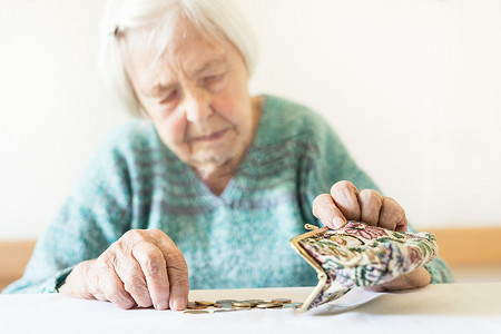 忧心忡忡的老妇人坐在桌旁数着钱包里的钱。