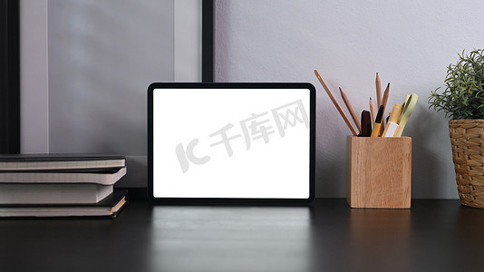 天猫电脑端摄影照片_在黑桌上模拟数字平板电脑、笔架、相框和室内植物。