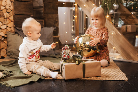 弟弟和妹妹在圣诞节前夕在为新年假期装饰的漂亮房子里玩耍。