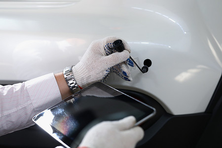 汽数字摄影照片_戴白手套的男性汽车机械手拿着现代数字平板电脑和汽车管