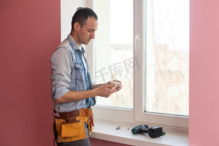安装程序工具摄影照片_工人在房子里安装和检查窗户。