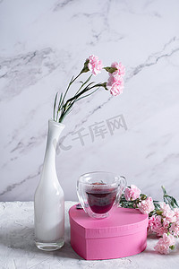 盒子粉色摄影照片_白色花瓶里的粉色康乃馨和心形粉色盒子里的咖啡杯，