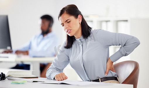 一位年轻的白人女商人在办公室里承受着腰痛的压力。