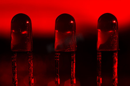 深红色背景中的三个圆形 LED 特写，宏观摄影