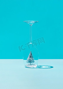 化学粉摄影照片_雪中​​的圣诞树在蓝色背景的酒杯内。