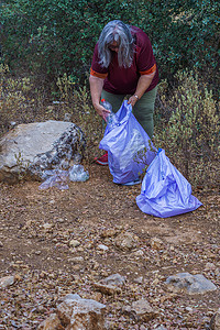 环保捡垃圾摄影照片_女生态学家带着垃圾袋从田间捡垃圾