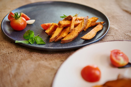煮红薯摄影照片_自制煮红薯配香料和香草，在蓝色陶瓷盘上配迷迭香和樱桃番茄