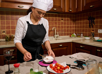 西红柿白糖摄影照片_多民族妇女在厨房秤上称量白糖，计算家庭厨房中制作腌料的原料质量
