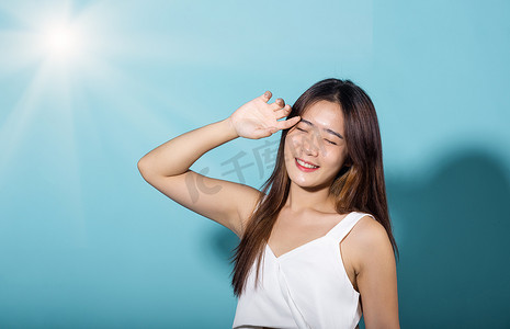 亚洲年轻女性举手遮脸保护阳光和紫外线微笑