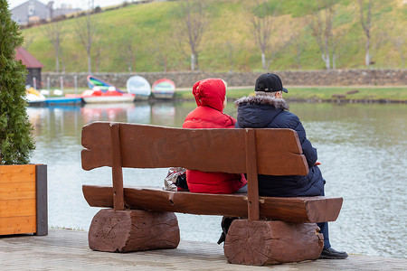老年男女坐在湖边的长凳上