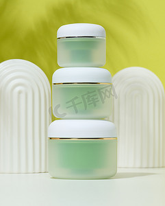 桌子上的罐子摄影照片_白色桌子上的化妆品绿色罐子。