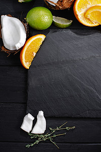 一套热带石灰水果模型，椰子，橙色，旧深色木桌的背景，顶视图，平坦