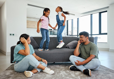 家庭、活力和孩子们在家里的沙发上跳跃，疲惫的父母与顽皮、多动和玩耍的孩子们作斗争。