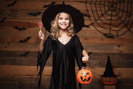 万圣节女巫概念 — 小女巫孩子带着万圣节甜蜜和糖果，带着欢快的微笑。
