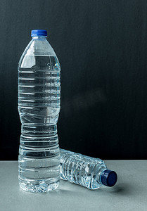 蓝色的矿泉水瓶子摄影照片_两个装满矿泉水的塑料瓶