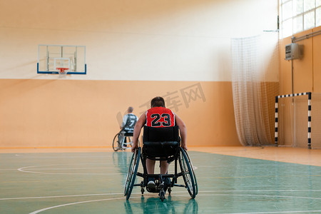 坐在球上的男孩摄影照片_男孩坐在轮椅上，为大竞技场的篮球比赛做准备
