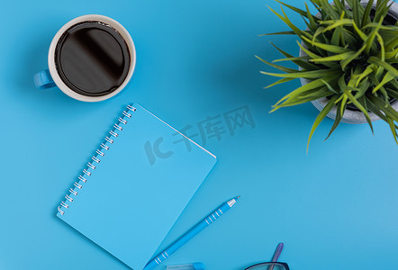 咖啡杯套样机摄影照片_工作空间蓝色套记事本、笔、眼镜和咖啡杯