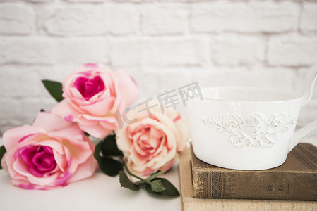 粉色浪漫玫瑰花束摄影照片_白桌上的玫瑰花束、旧书上的一大杯咖啡、浪漫的花框背景、花卉风格的墙壁模型、玫瑰花模型、情人节母亲节卡片、礼品卡