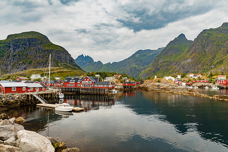 罗弗敦群岛，经典的挪威风景，海岸上红色的小渔屋，一艘小船，岩石海岸和戏剧性的天空