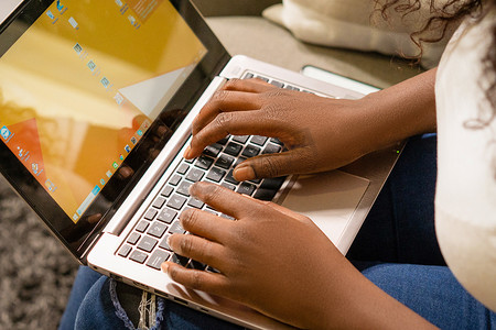 女手在笔记本电脑键盘上打字，黑皮肤的人在笔记本电脑上工作。