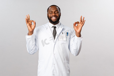穿着白大褂的非洲裔美国英俊医生的肖像，闭上眼睛，表现得很好，完美的标志，带着高兴的微笑，科学家终于在实验室发现了 covid19 疫苗