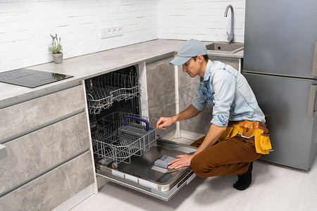 男人在厨房里打开或关闭洗碗机。