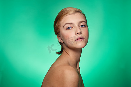 护肤品绿色背景摄影照片_皮肤清洁的女性面部手术美容裸肩绿色背景