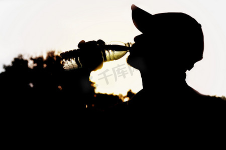 一名男子运动后从瓶子里喝水的特写。