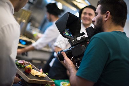 摄像发布摄影照片_摄像师在团队厨师和厨师准备饭菜时录制