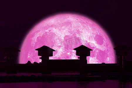 夜空中的超级草莓粉色月亮和剪影水坝
