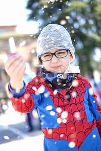 穿着红蜘蛛超级英雄服装的漂亮孩子玩五彩纸屑