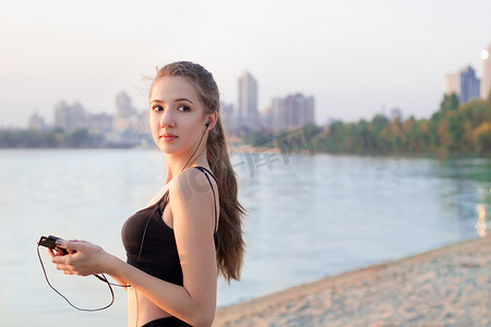 湖边用手机听音乐的健身女人