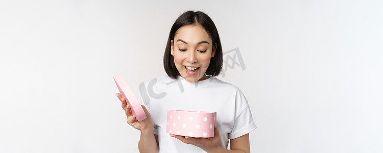 中打开的盒子摄影照片_快乐的亚洲女人，女朋友打开带情人节礼物的盒子，收到浪漫礼物，站在白色背景中