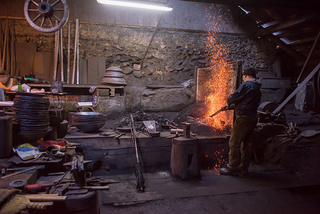 传统铁匠摄影照片_年轻的传统铁匠与明火一起工作